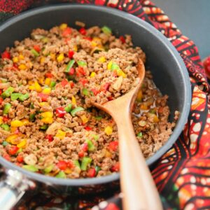 Vibrant picadillo cooked with red, green, and yellow bell peppers in a pan.